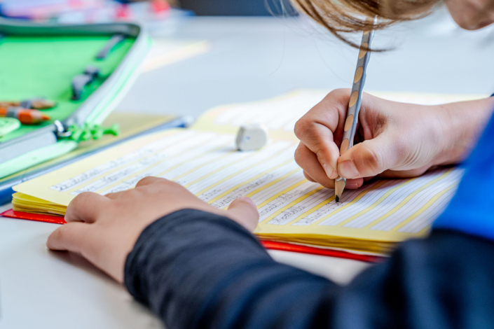 Ein Schüler bei Schreibübungen mit Bleistift im Schulhef