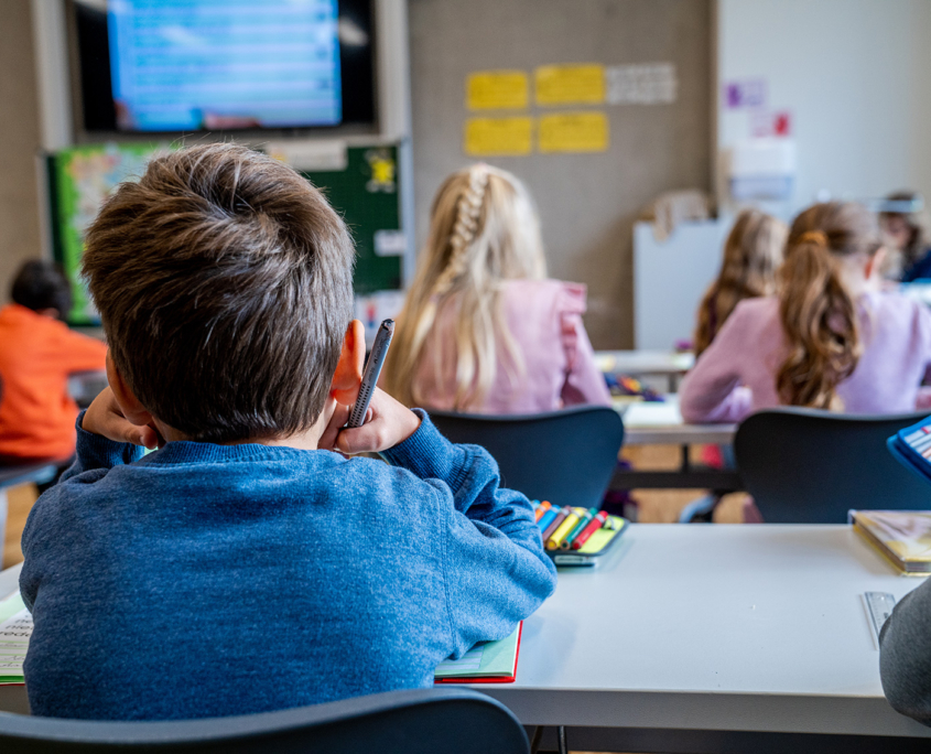 Schüler sitzen in der Klasse mit Videotafel